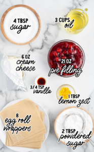 Ingredients for air fryer cherry cheesecake rolls, including egg roll wrappers, cream cheese, sugar, and cherry pie filling.