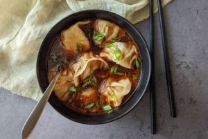 Dumplings cooking gently in a pot of broth.