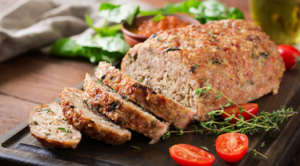 Traditional meatloaf with ketchup glaze on a wooden table.